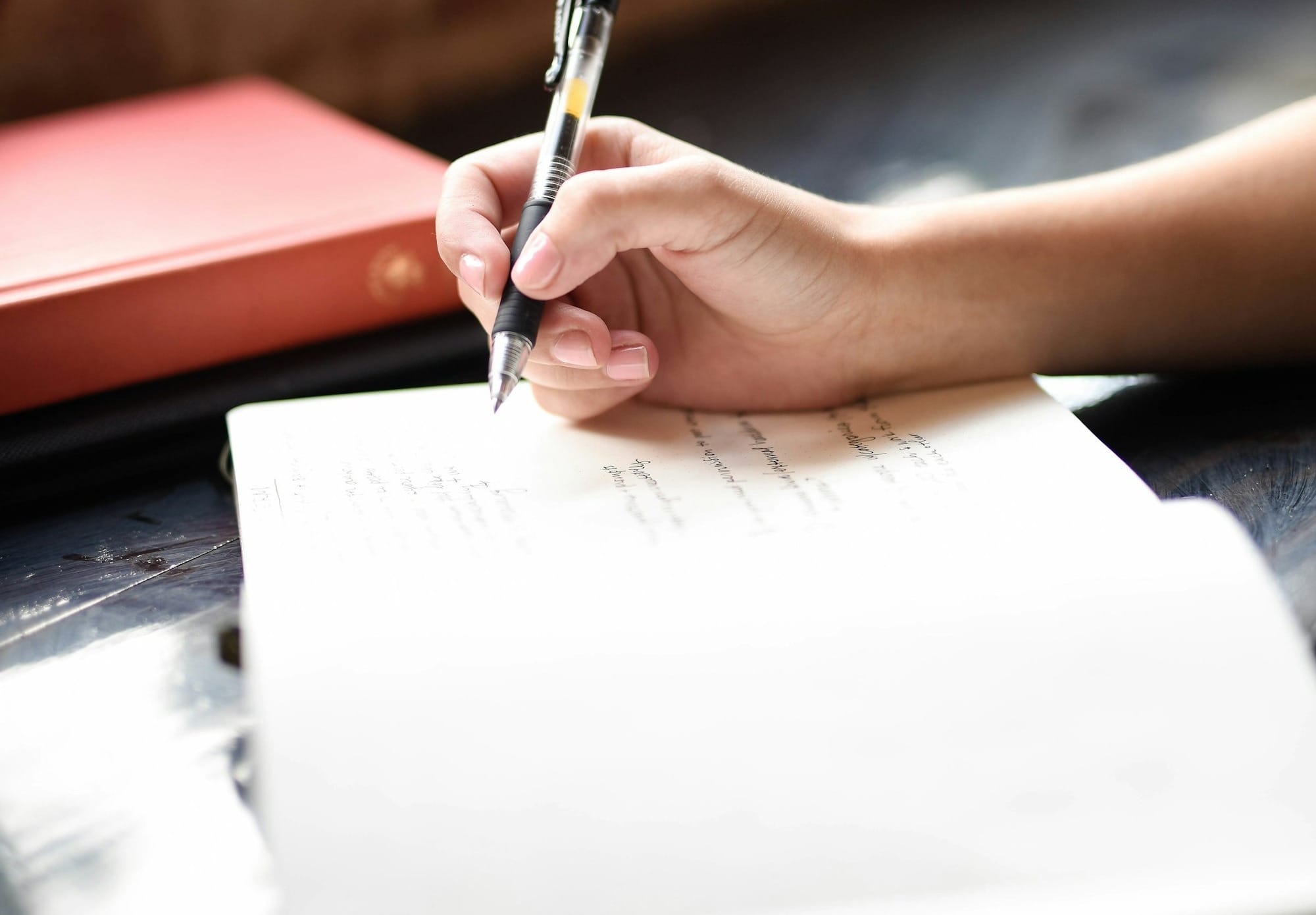 a person writing on a piece of paper with a pen