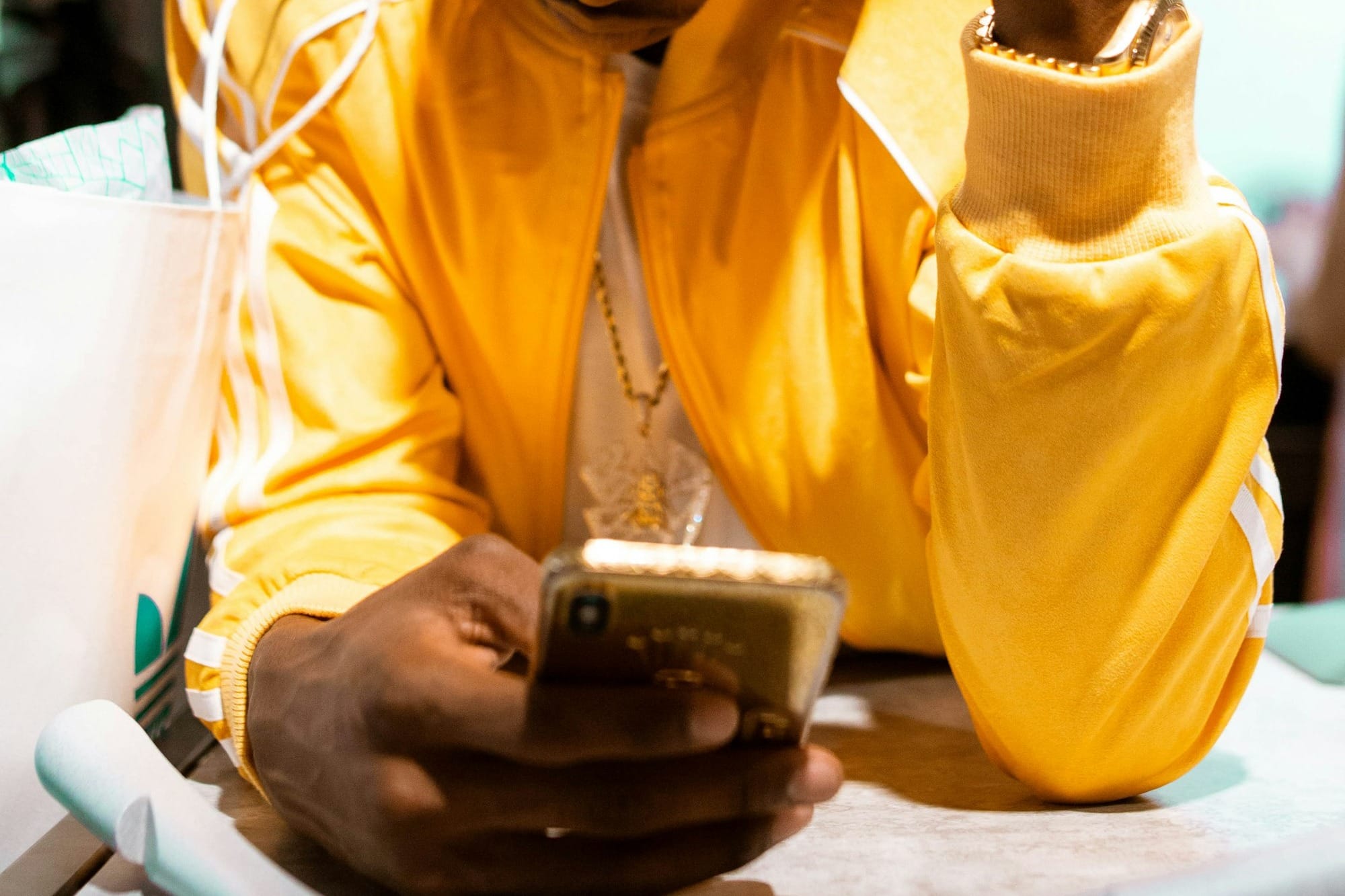 man in yellow dress shirt holding gold iphone 6