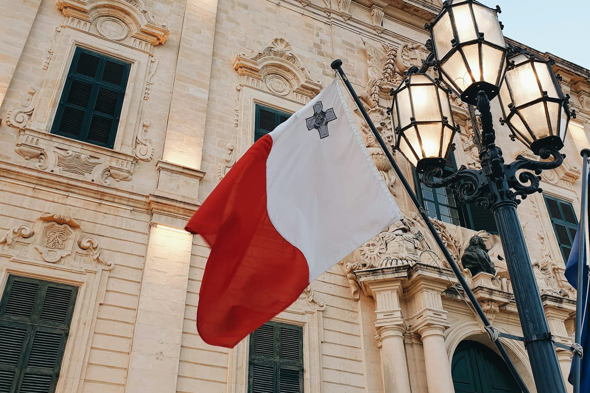 a flag hanging from a lamp post in front of a building