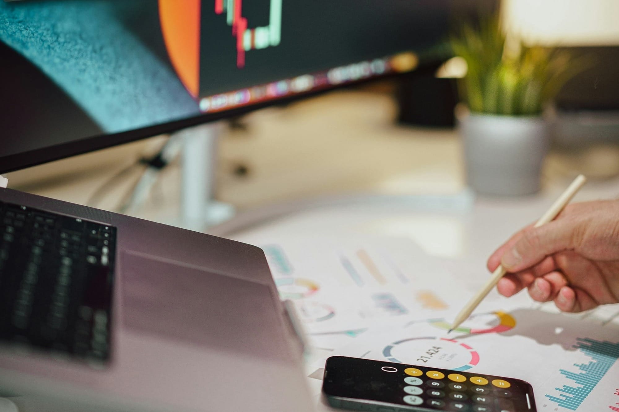 a person writing on a piece of paper next to a computer monitor