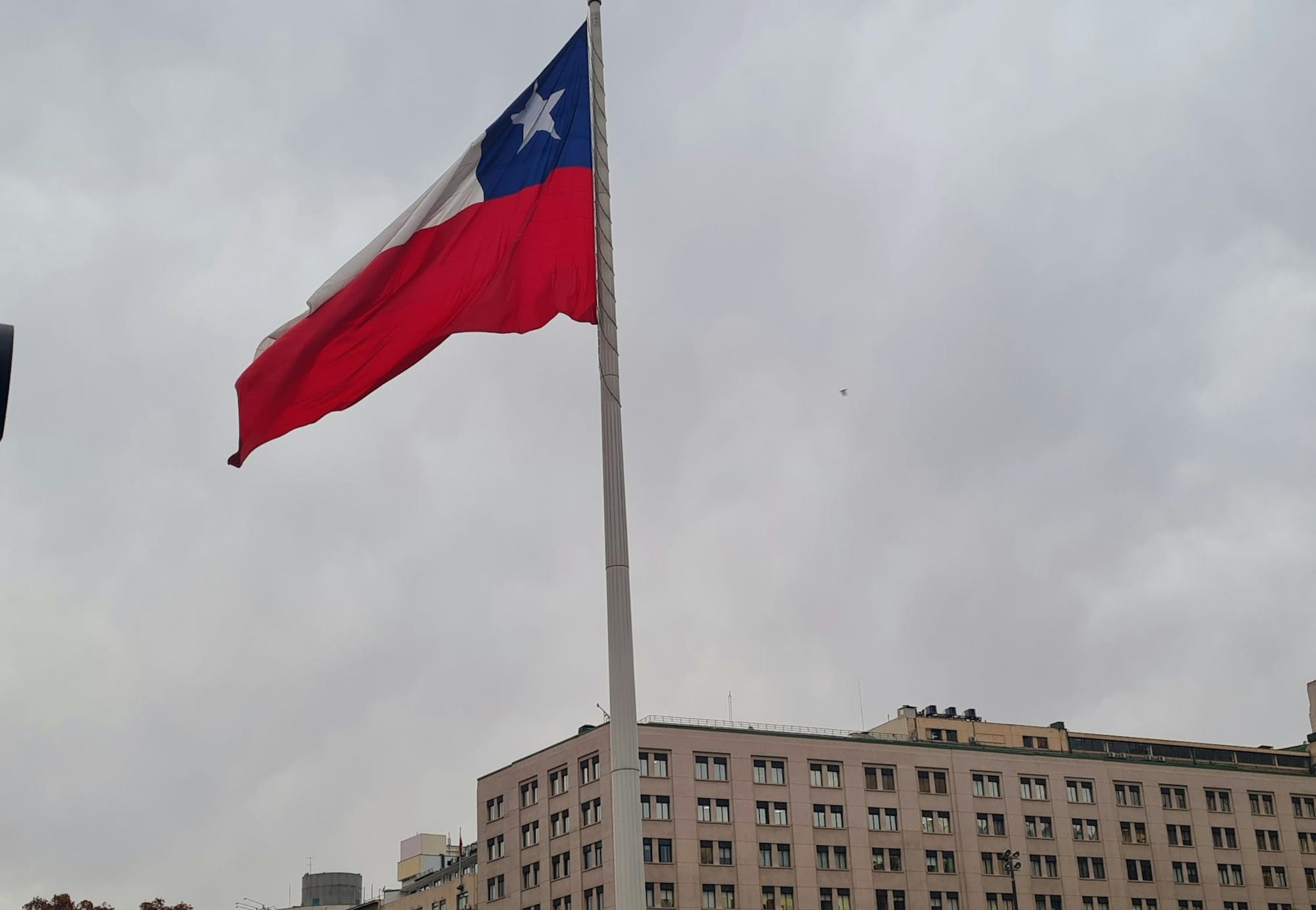 a flag flying in the wind next to a tall building