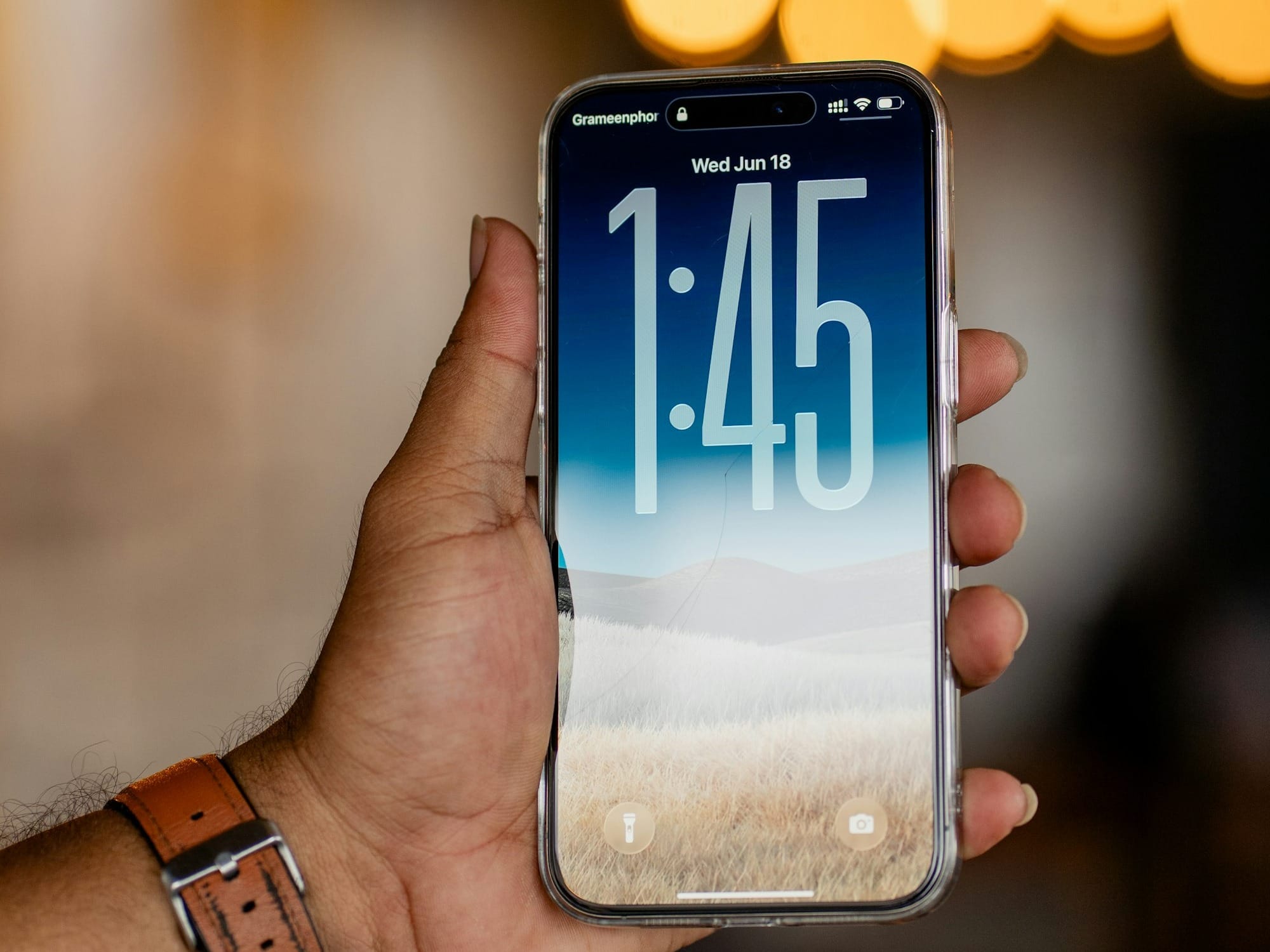 A hand holds a phone with the time displayed