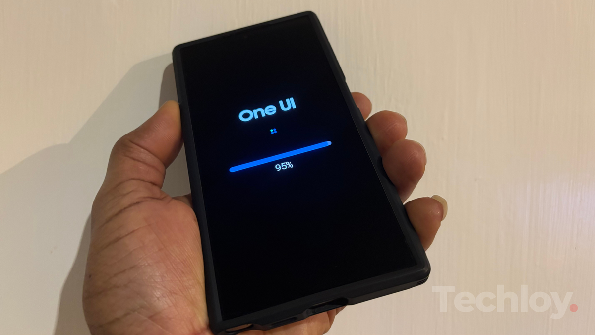 A hand holding a smartphone displaying the "One UI" logo and a progress bar at 95% on the screen.