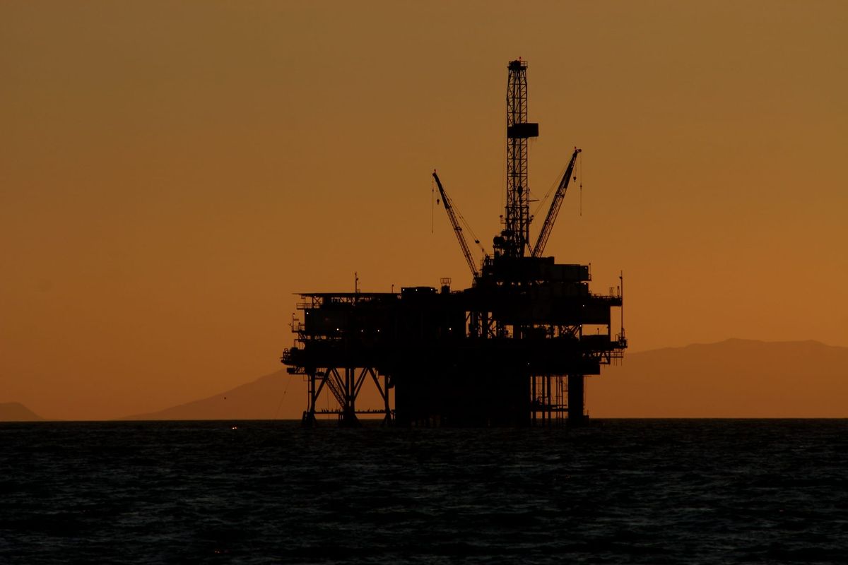 A silhouetted oil rig at night. photo by arbyreed