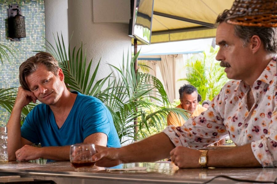 Steve Zahn as Mark and Murray Bartlett as Armond in The White Lotus. The men are seated at a bar in conversation.