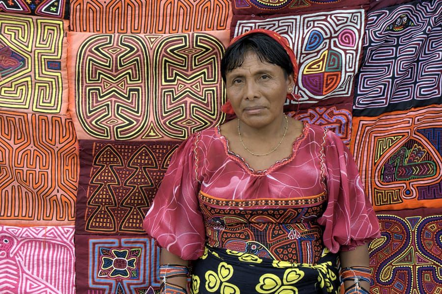 A colorful photograph of a Guna woman selling molas in Panama City.