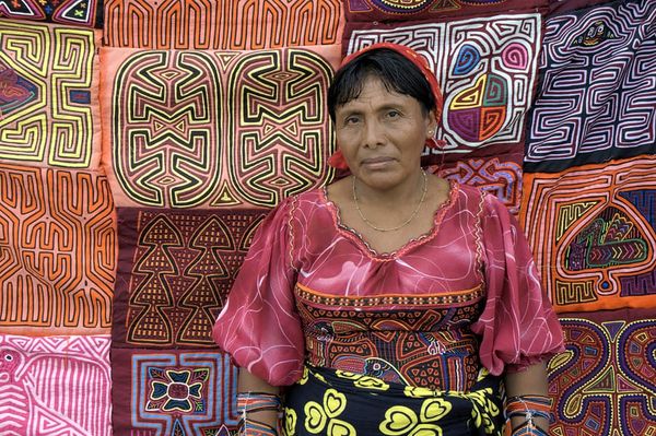 A colorful photograph of a Guna woman selling molas in Panama City.