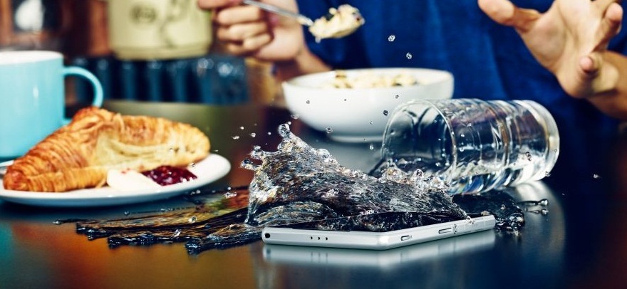 'A glass of water spilling onto a smartphone'