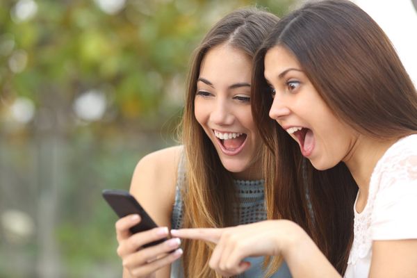 Two friends point to a smartphone