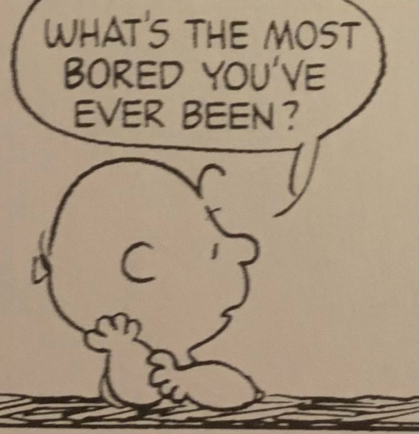 A panel from a Peanuts comic strip showing Charlie Brown resting his head on one elbow and asking someone off-panel, "What's the most bored you've ever been?"