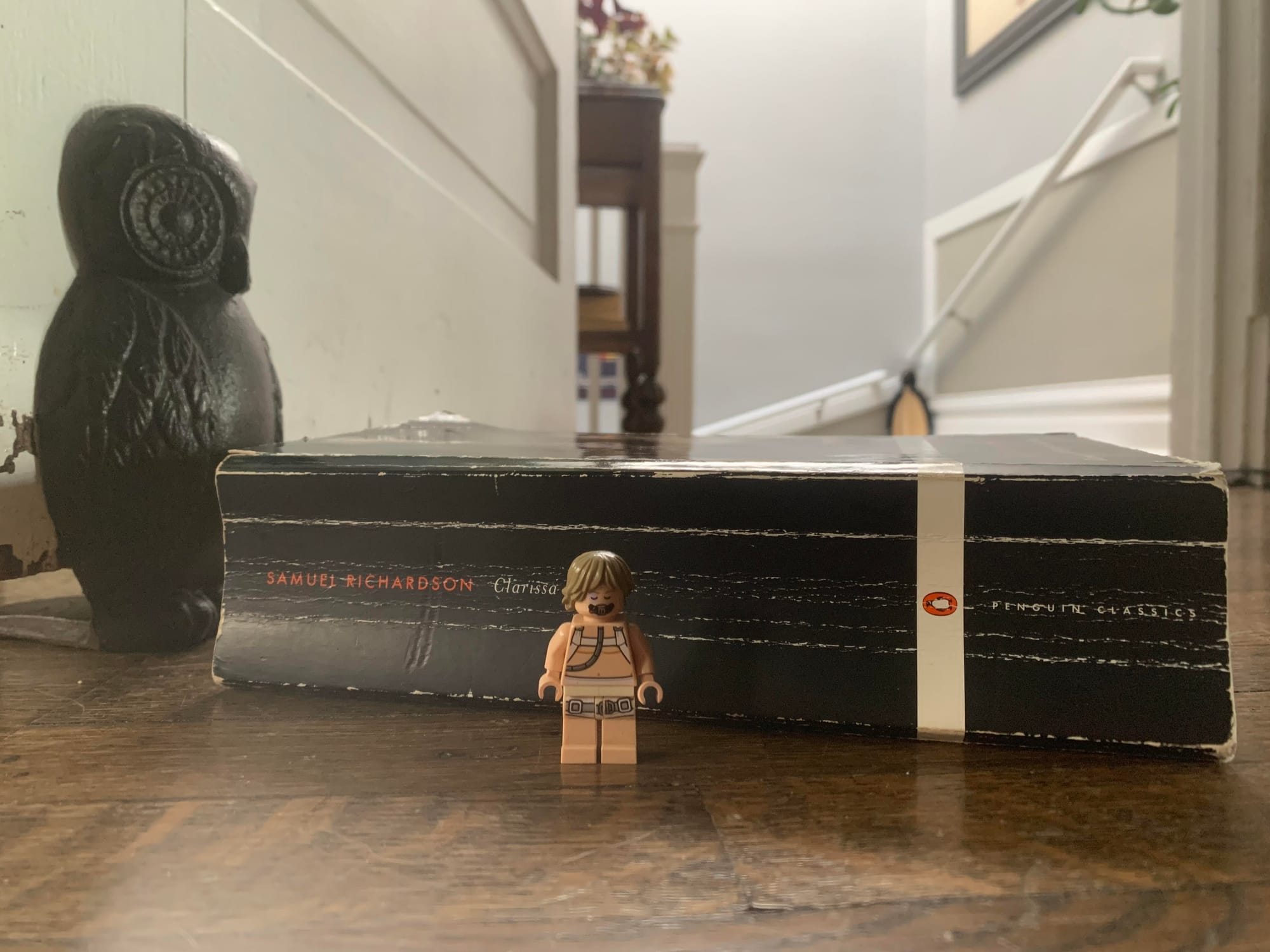 The Penguin Classic edition of Clarissa, seen on its side with a Lego minifig of Luke Skywalker in the healing bacta tank for scale, a metal owl doorstop behind it.