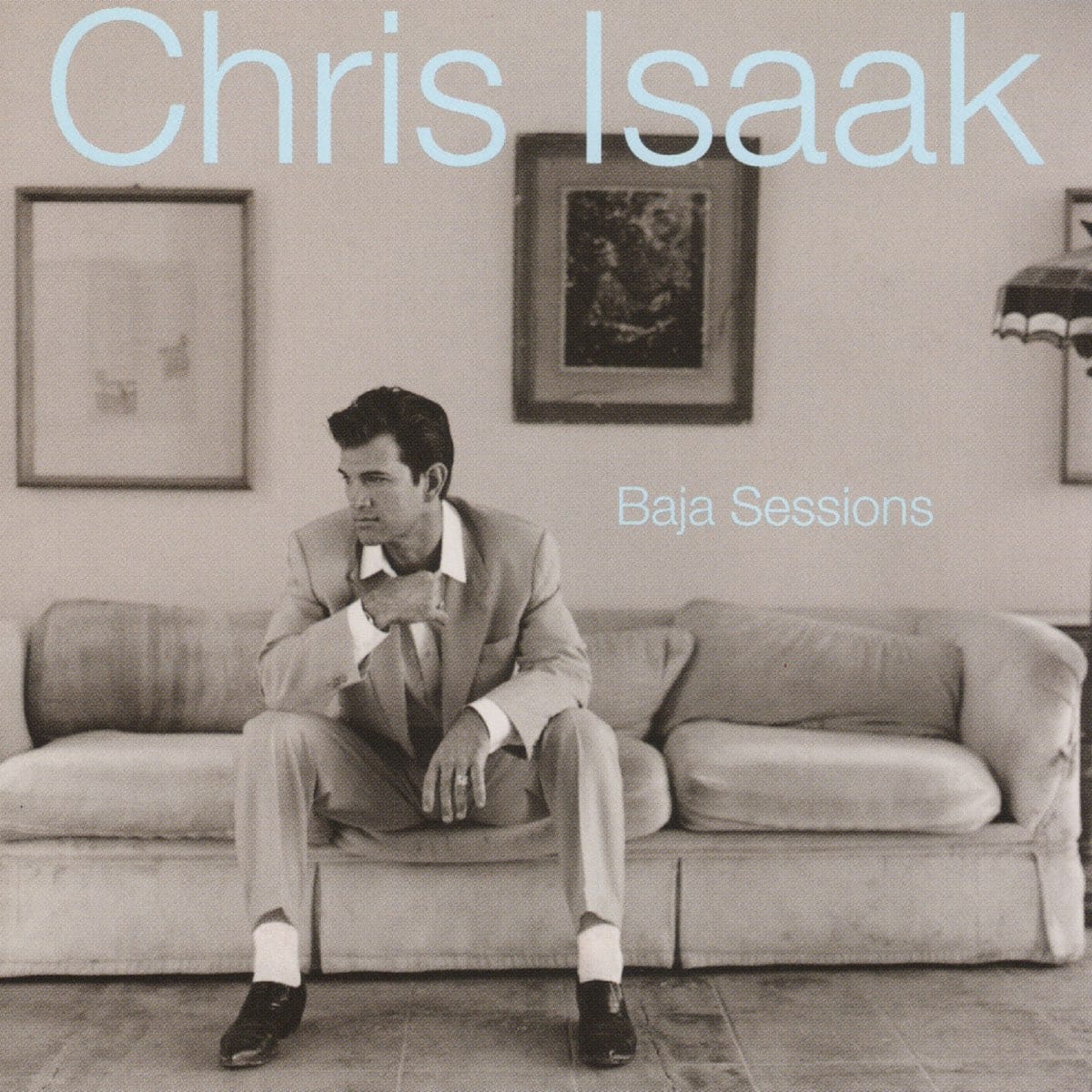 The cover of The Baja Sessions, which features a black-and-white photo of Chris Isaak in a light-colored suit and open-collared shirt sitting on a low couch.