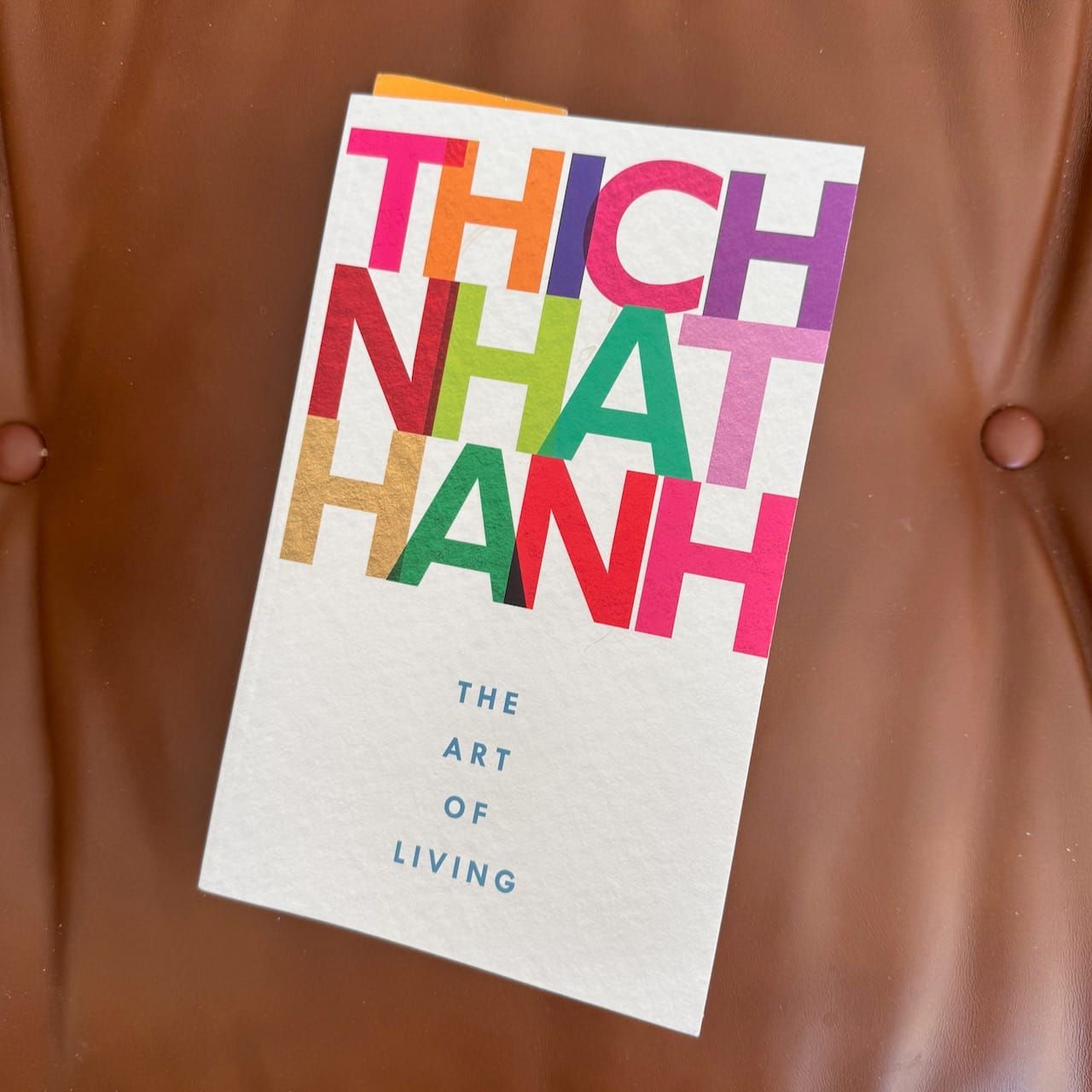 Book cover of The Art of Living by Thich Nhat Hanh on a leather footstool