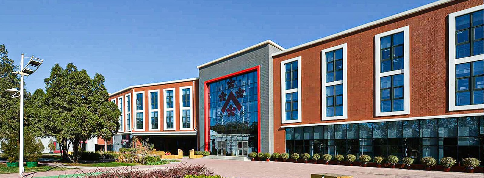 Academic building featuring modern architecture with red brick exterior, extensive glazing, and geometric entrance element.