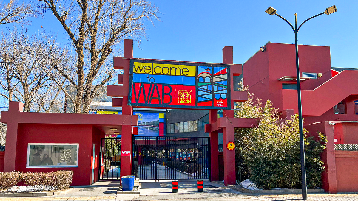Western Academy of Beijing campus gate featuring distinctive red architecture and entrance barriers.