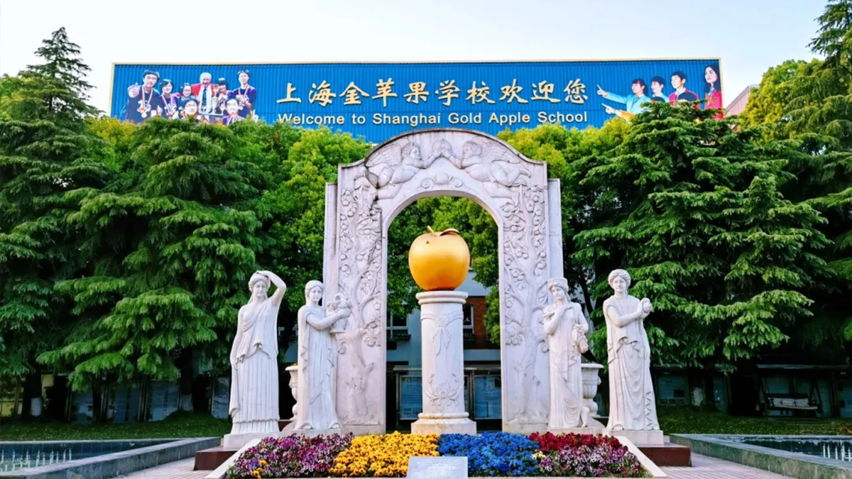 Shanghai Gold Apple School entrance showing a sculptural monument with a golden apple centerpiece and colorful flowers.