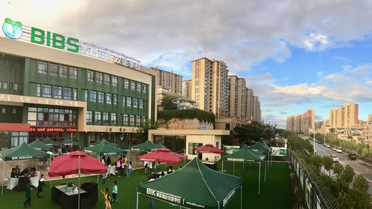 Beanstalk International Bilingual School Kunming campus with green tents, outdoor activities, and surrounding residential towers.
