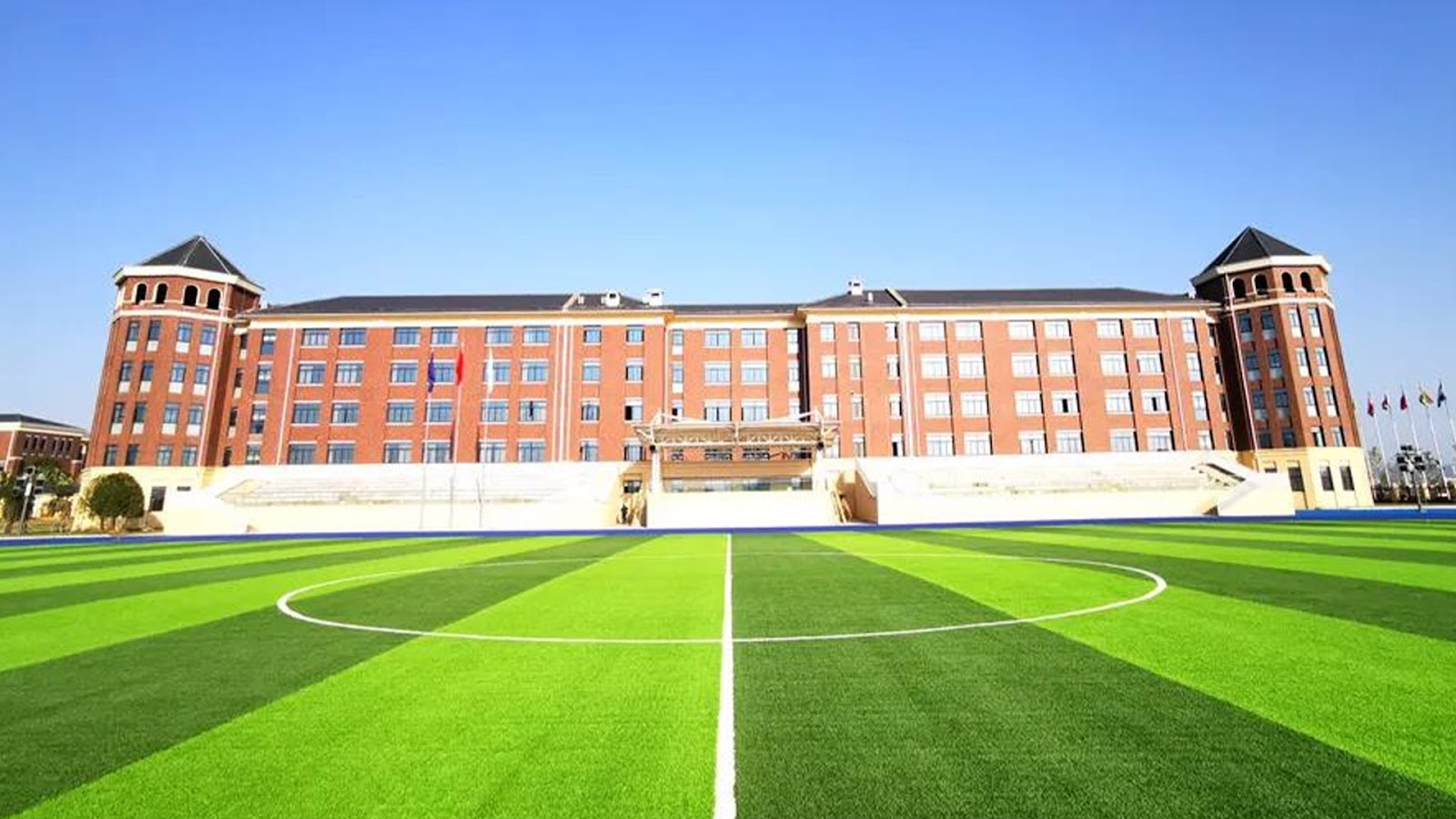 Yiwu International Academy campus building with a green soccer field and China international school facilities.