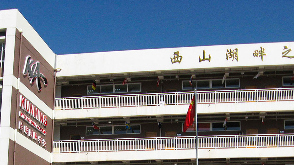 Kunming International Academy building showing bilingual signage and colorful international flag decorations.