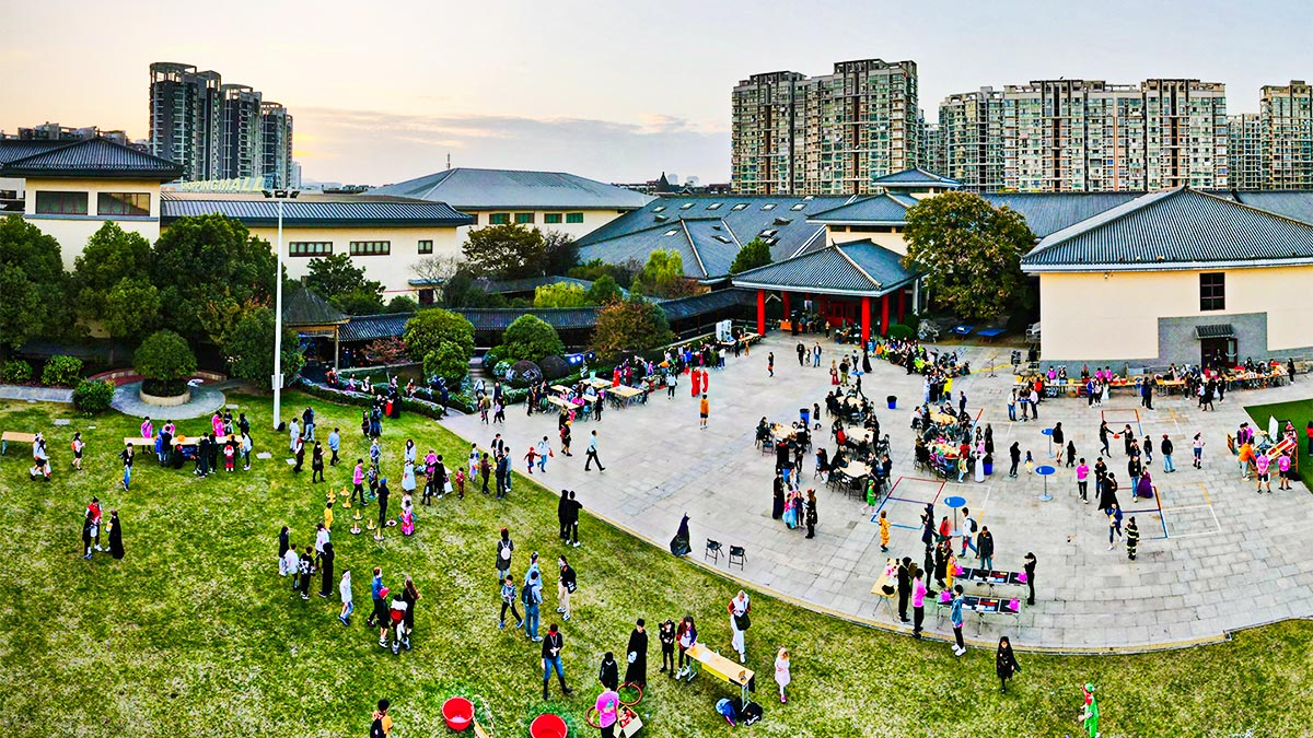 Nanjing International School campus with students gathered for an outdoor event.