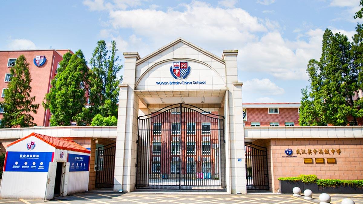 Wuhan Britain-China School entrance gate with colonial architecture and manicured grounds under blue sky.