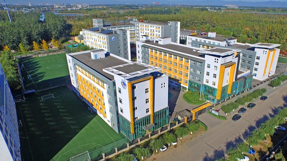Beijing International Bilingual Academy campus with orange accents and green sports fields.