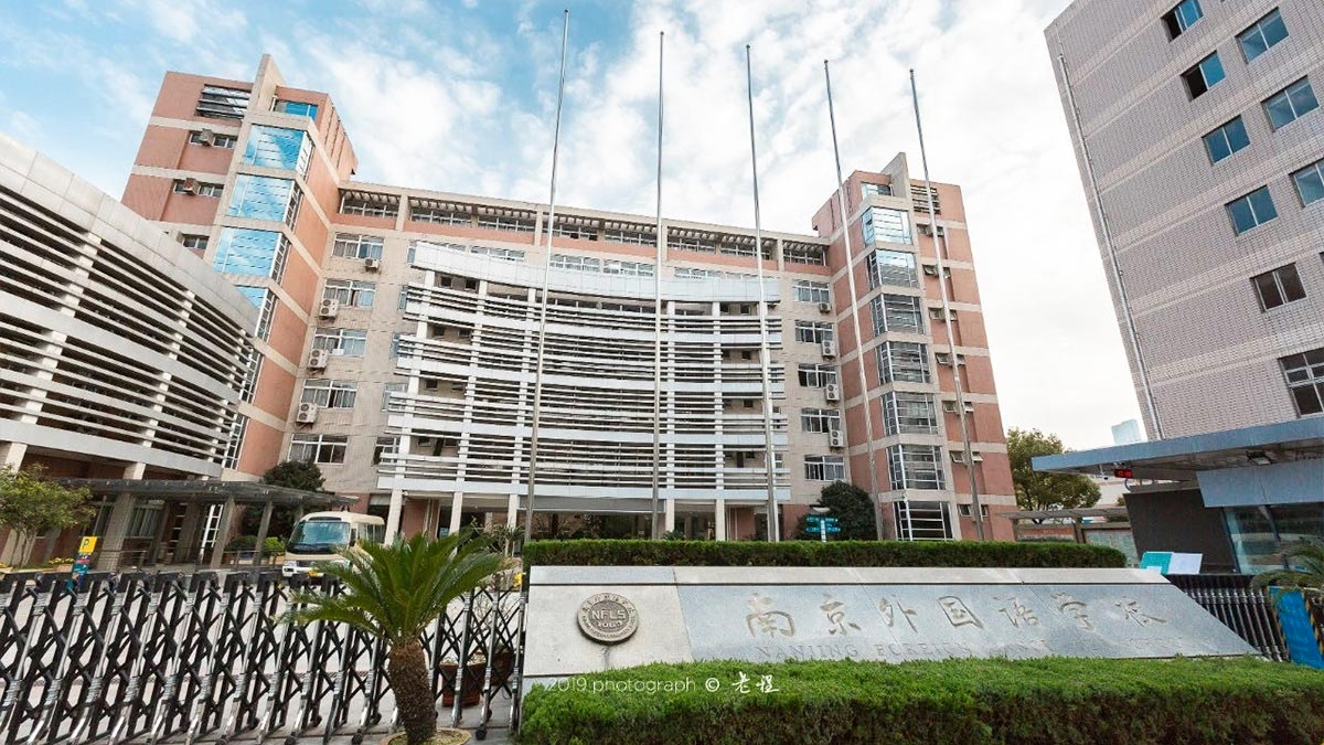 Nanjing Foreign Language School entrance with modern multi-story buildings and flagpoles in courtyard.
