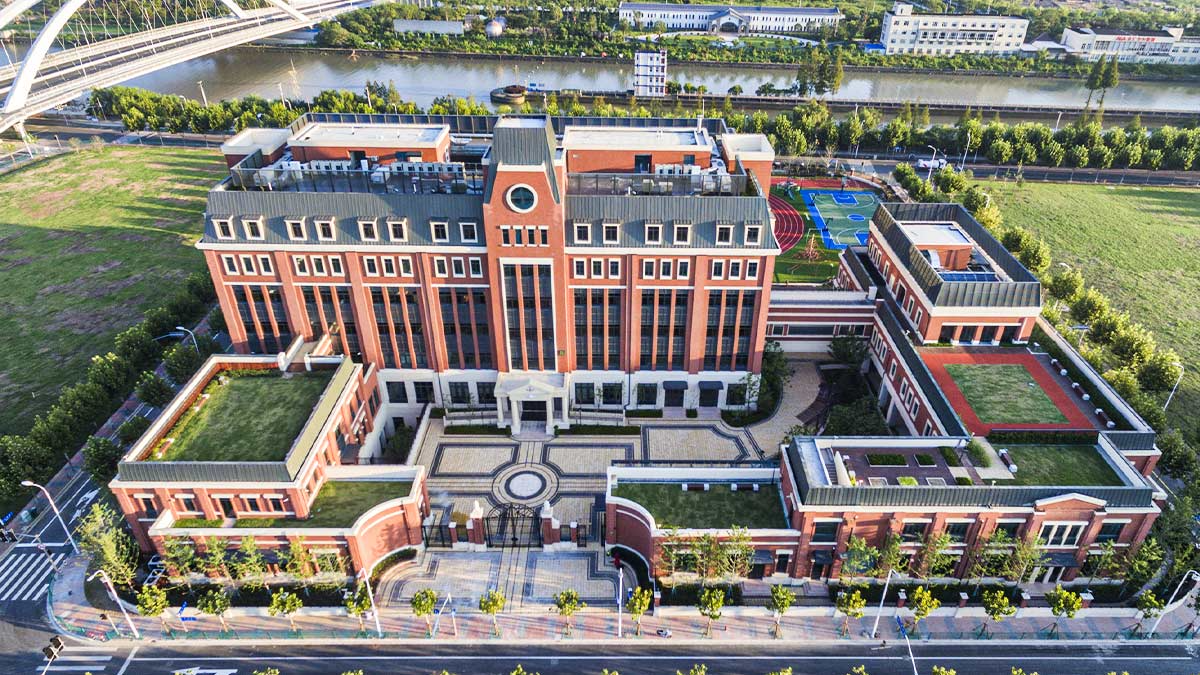 Huili School Shanghai aerial view showcasing red brick architecture with sports facilities and landscaped grounds.