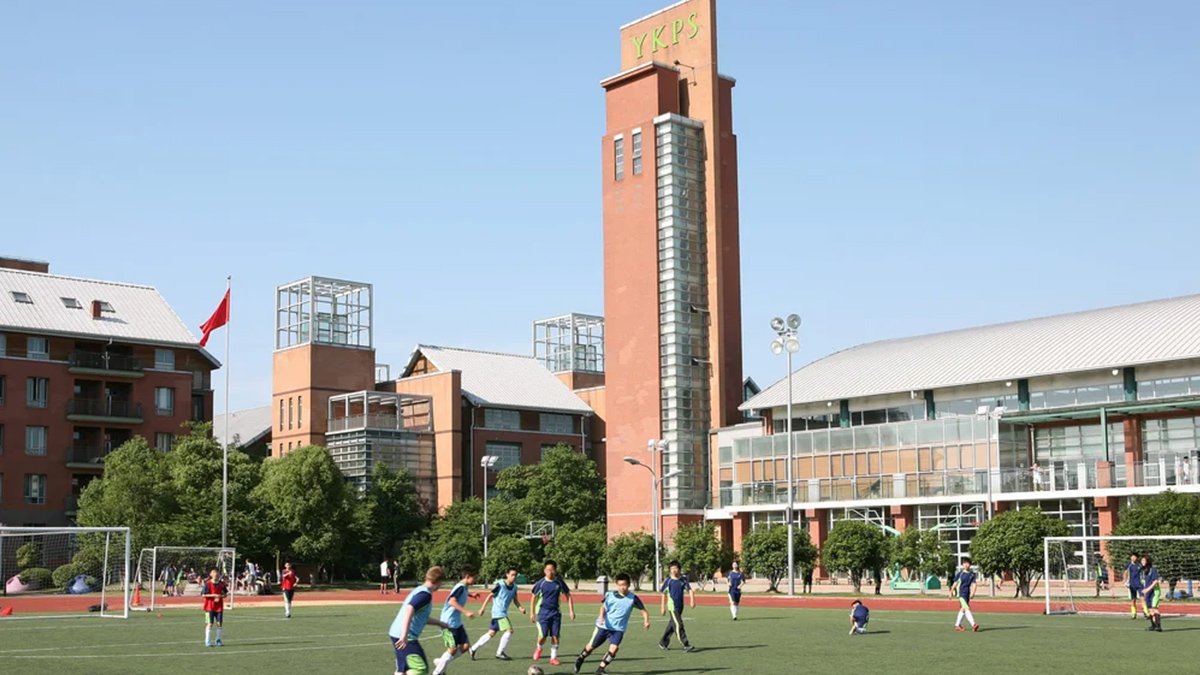 YK Pao School campus with distinctive clock tower and students playing soccer outdoors.