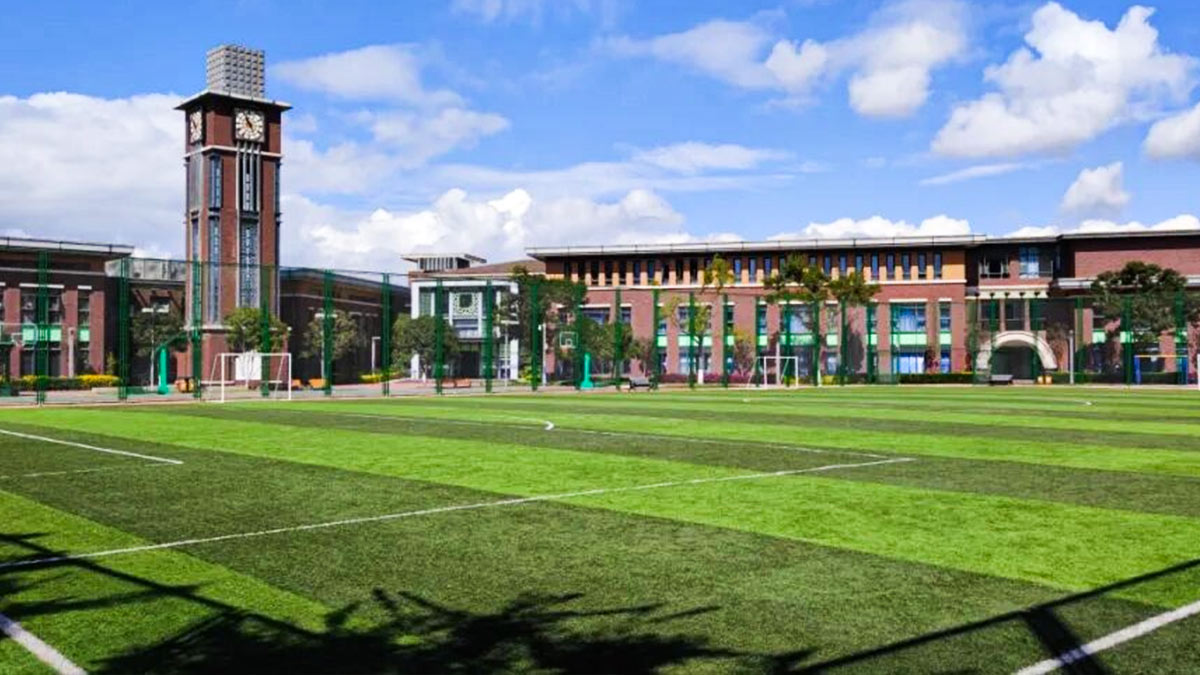 Kunming Concord College of Sino-Canada campus view with iconic tower, modern architecture, and manicured playing field.
