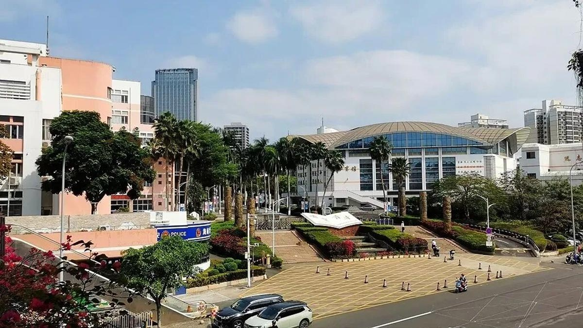 Hainan Overseas Chinese Middle School campus view with modern dome building palm trees and landscaped courtyard entrance.