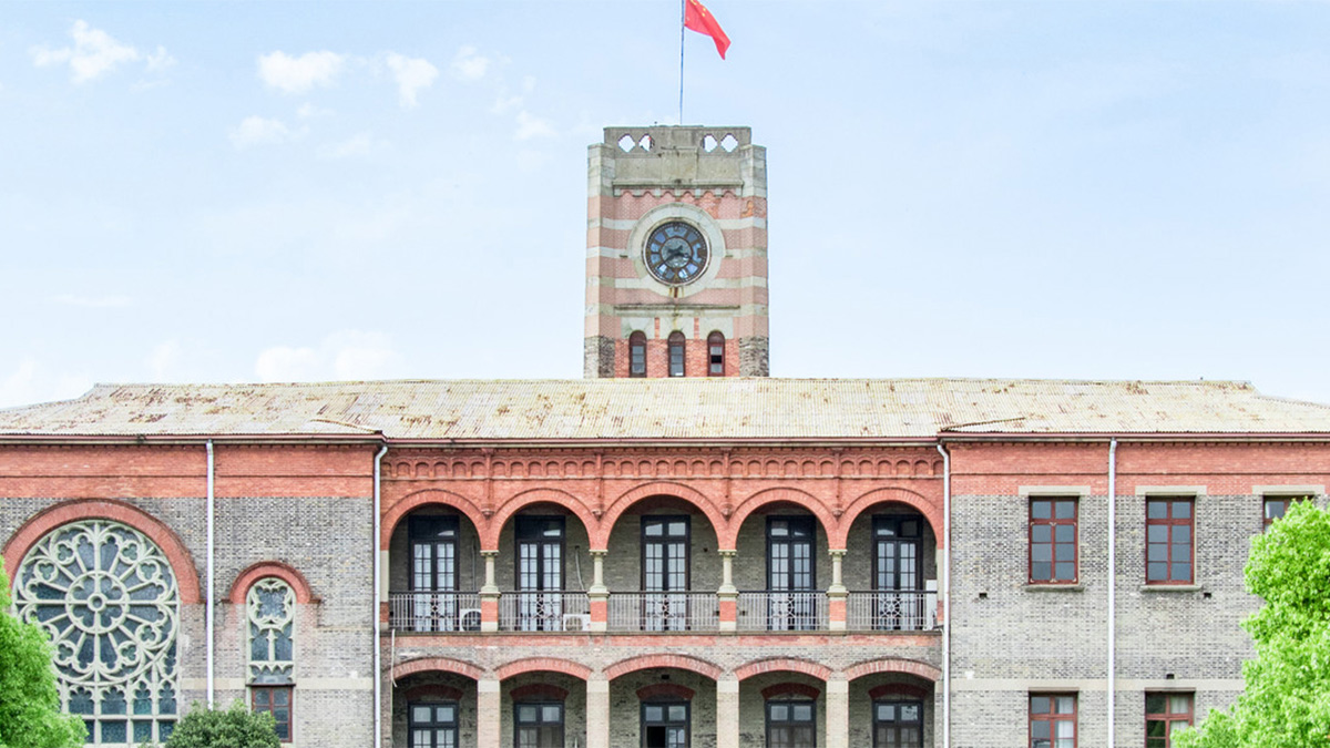 Maple Glory Education MGE historic campus building with clock tower arched balconies and Chinese flag in Xiamen.
