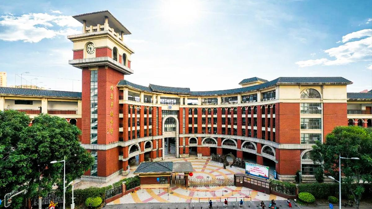 Guangdong Overseas Chinese Middle School red brick facade with clock tower arched entrance and blue tile roof architecture.