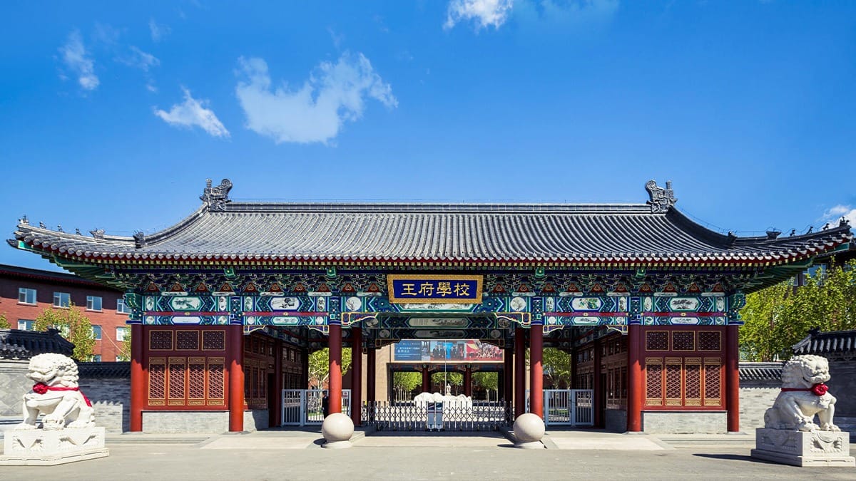 Beijing Royal School traditional Chinese entrance gate with ornate roof and guardian lion statues