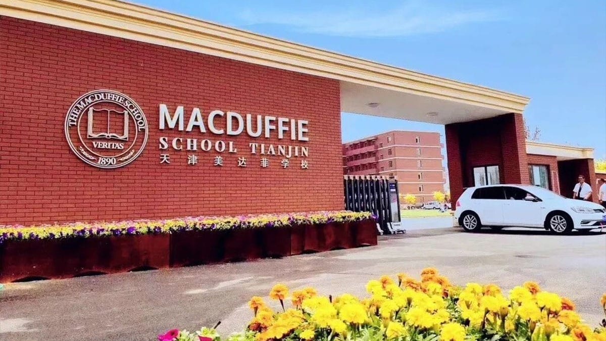 The MacDuffie School Tianjin entrance with red brick facade and colorful flower beds