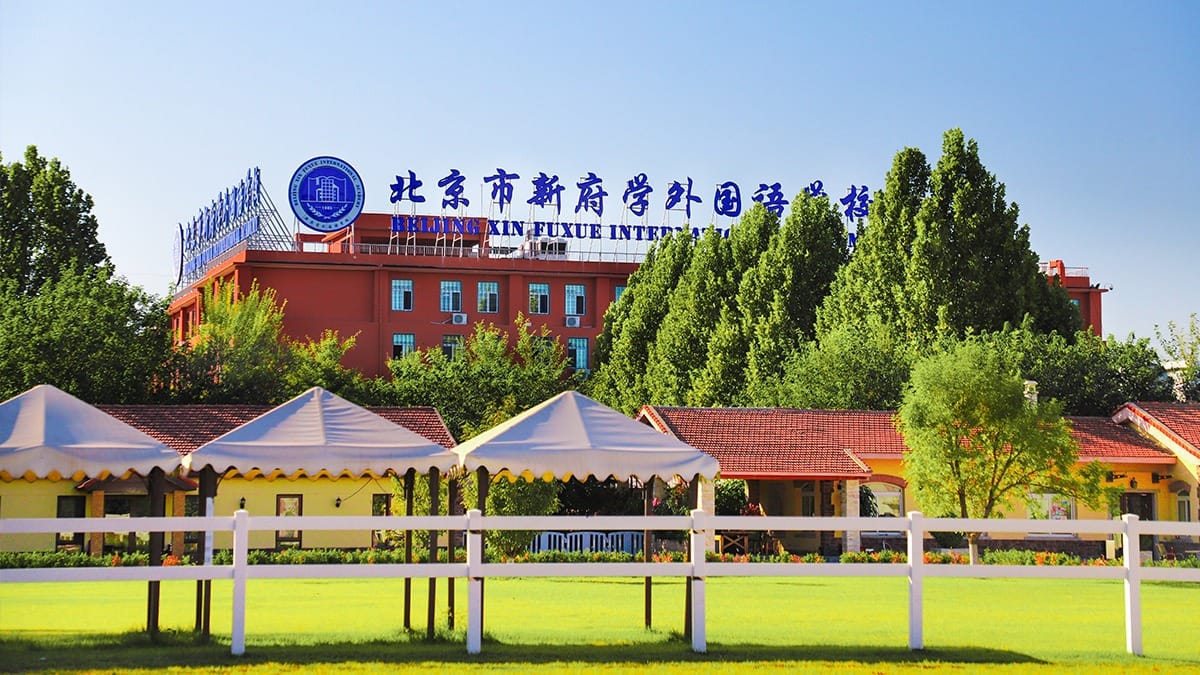 Beijing Xin Fuxue International Academy campus with sports field and yellow pavilions