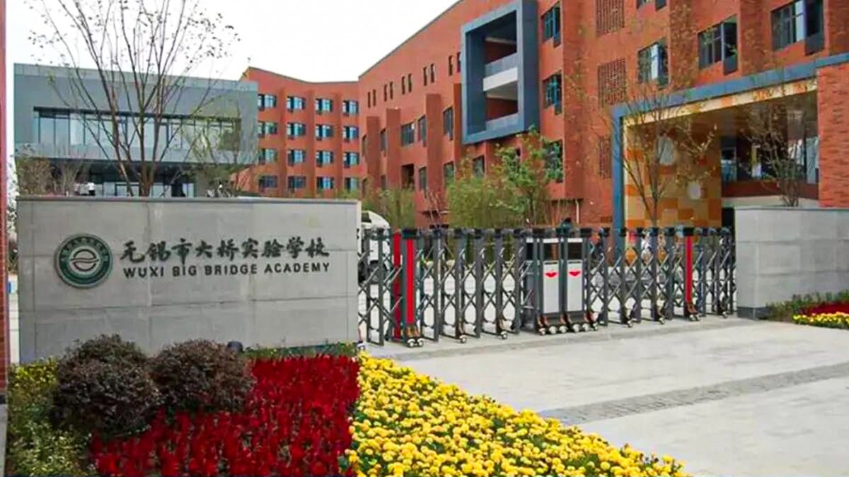 Wuxi Big Bridge Academy entrance with orange buildings, expandable gate, and colorful flowers