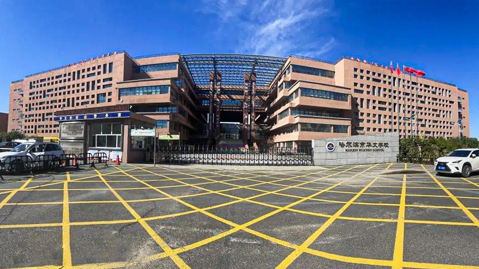 Harbin Huawen School main building entrance with parking lot and flags