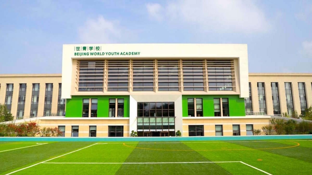 Beijing World Youth Academy building with green accents and sports field in foreground