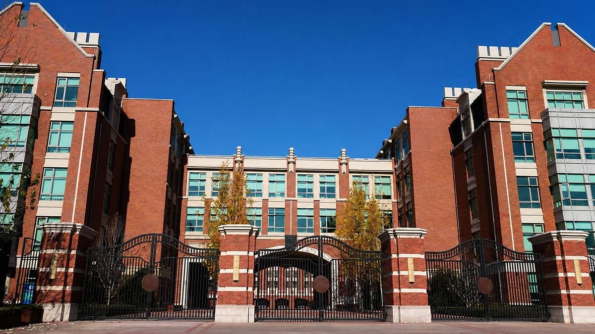 Beijing Keystone Academy grand brick campus with ornate iron gates and autumn trees