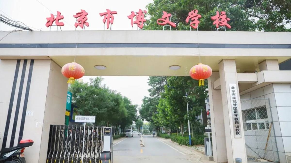 Beijing Bowen School entrance gate with red lanterns and tree-lined campus road