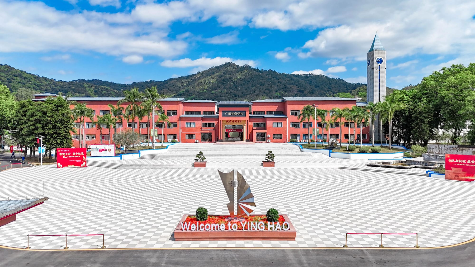 Guangzhou Yinghao School campus entrance plaza with red main building and clock tower