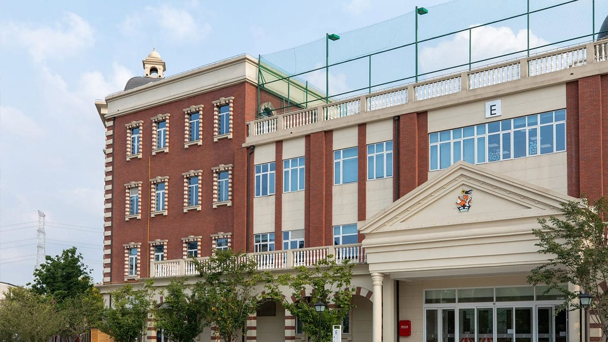 Wellington College Hangzhou red brick classical building with school crest and rooftop courts