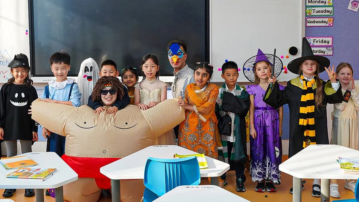 Multicultural primary students and international teacher in costumes at a cultural event in a Qingdao MINGDE School (QMDS) classroom — bilingual international school, Qingdao, Shandong