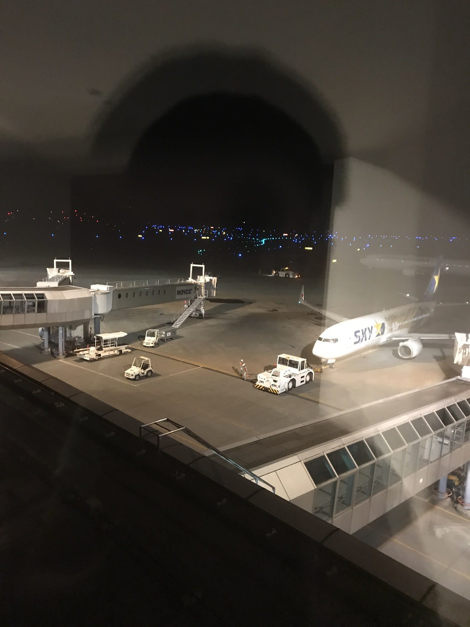 The night-time apron and aircraft seen through an Air Terminal Hotel room window