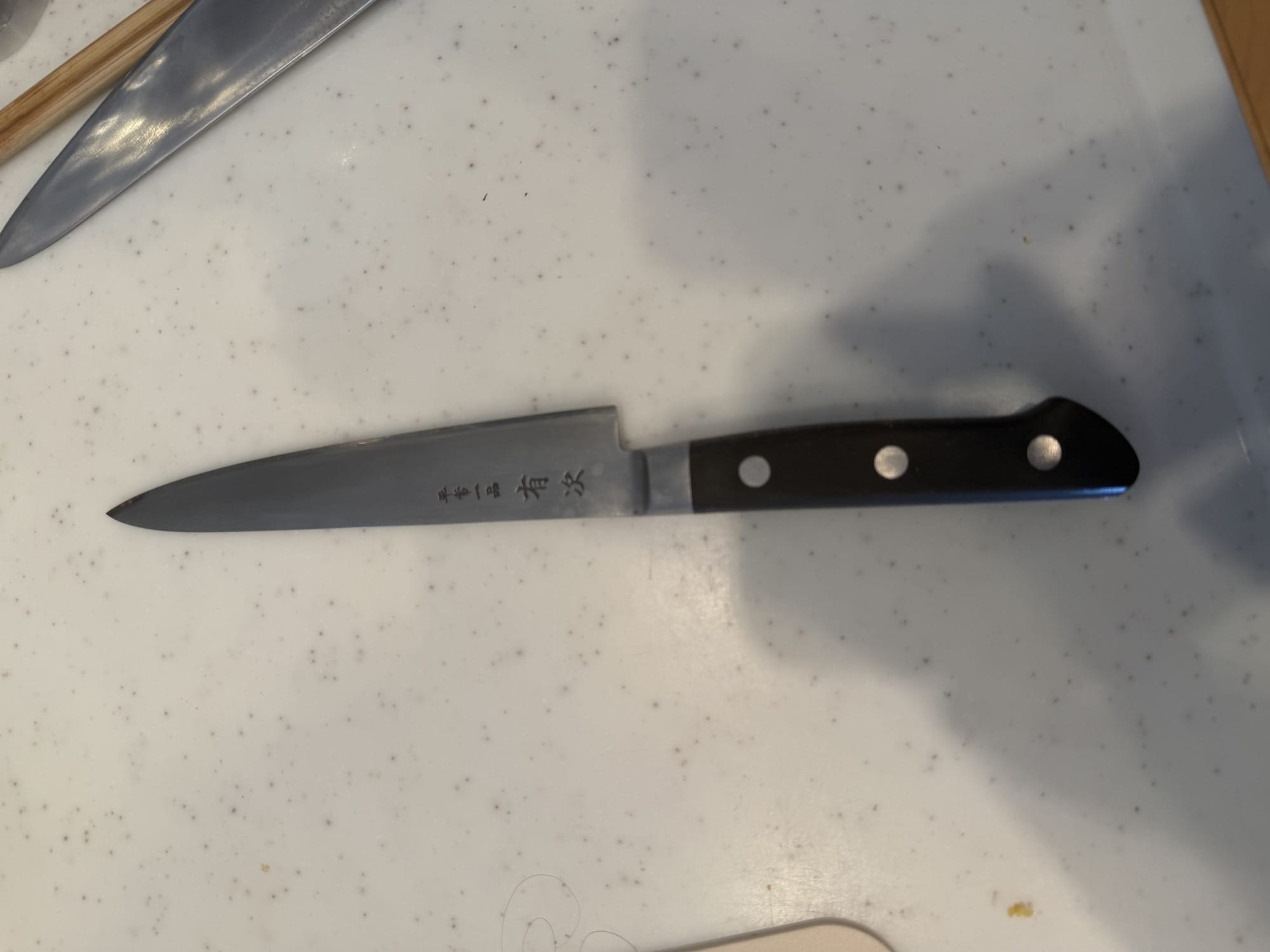 A well-used Aritsugu petty knife, twenty years old, with the Aritsugu maker's mark engraved on the blade