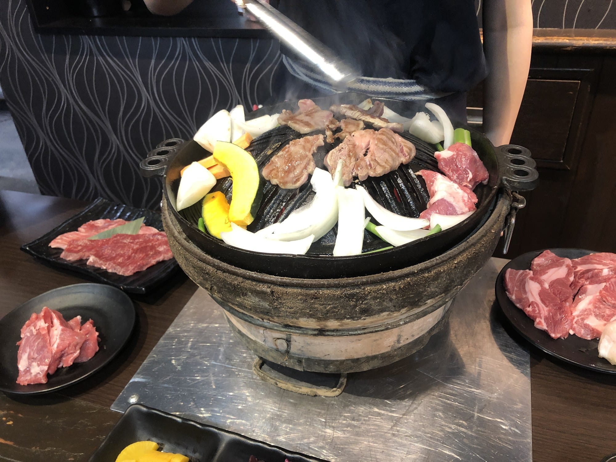 Lamb and vegetables grilling on a dome-shaped jingisukan pan