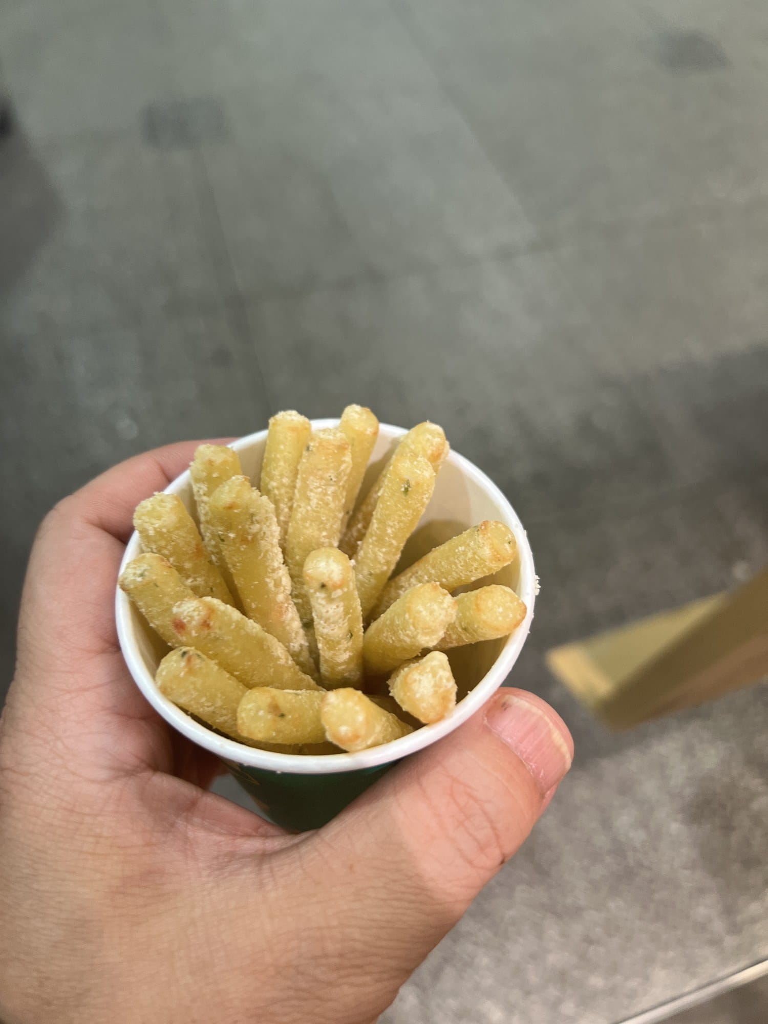 A paper cup of freshly fried Calbee potato snacks held in a hand