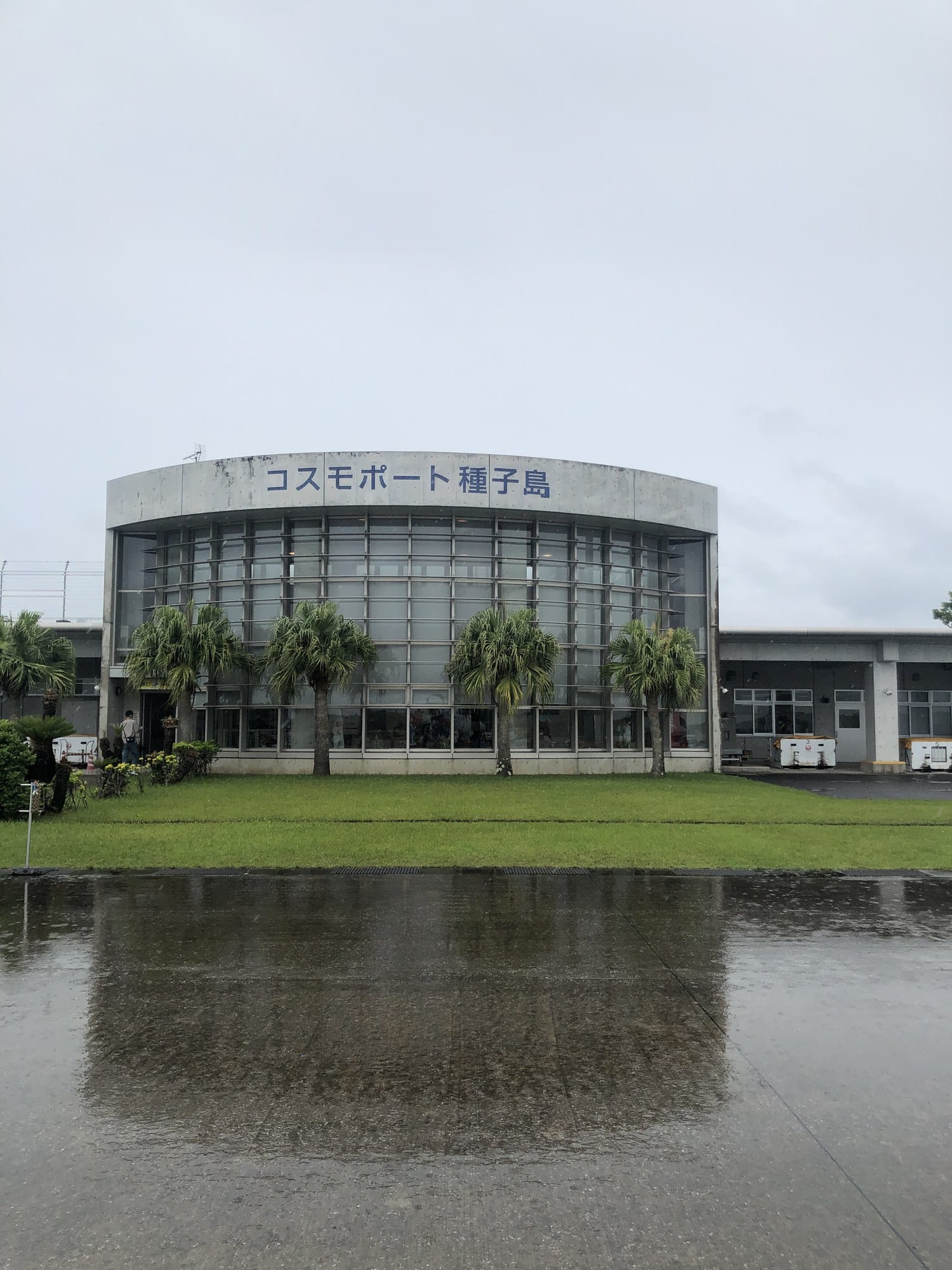 Curved glass terminal building of Tanegashima Airport with the sign Cosmoport Tanegashima