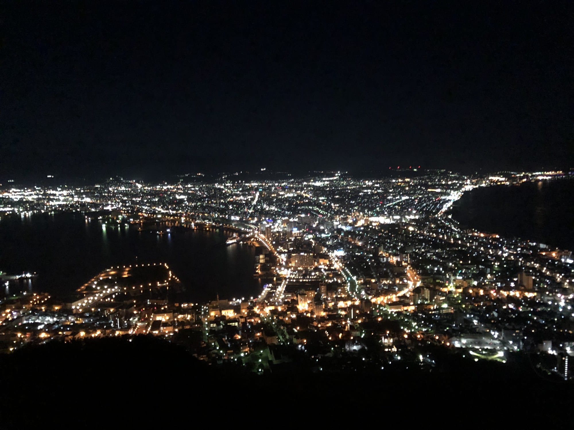 Panoramic night view of Hakodate from the Mt. Hakodate ropeway summit, city lights curving along the isthmus